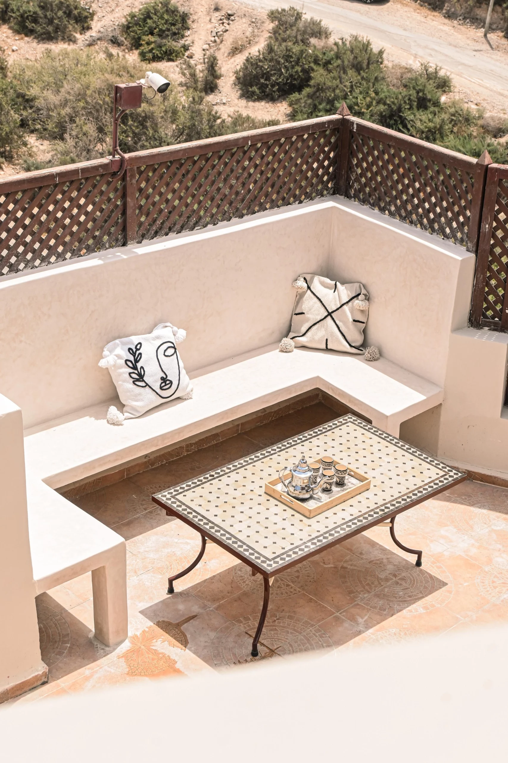 Salon d’extérieur sur la terrasse partagée de Berber Shelter, espace lounge ensoleillé avec vue sur les collines de Tamraght.