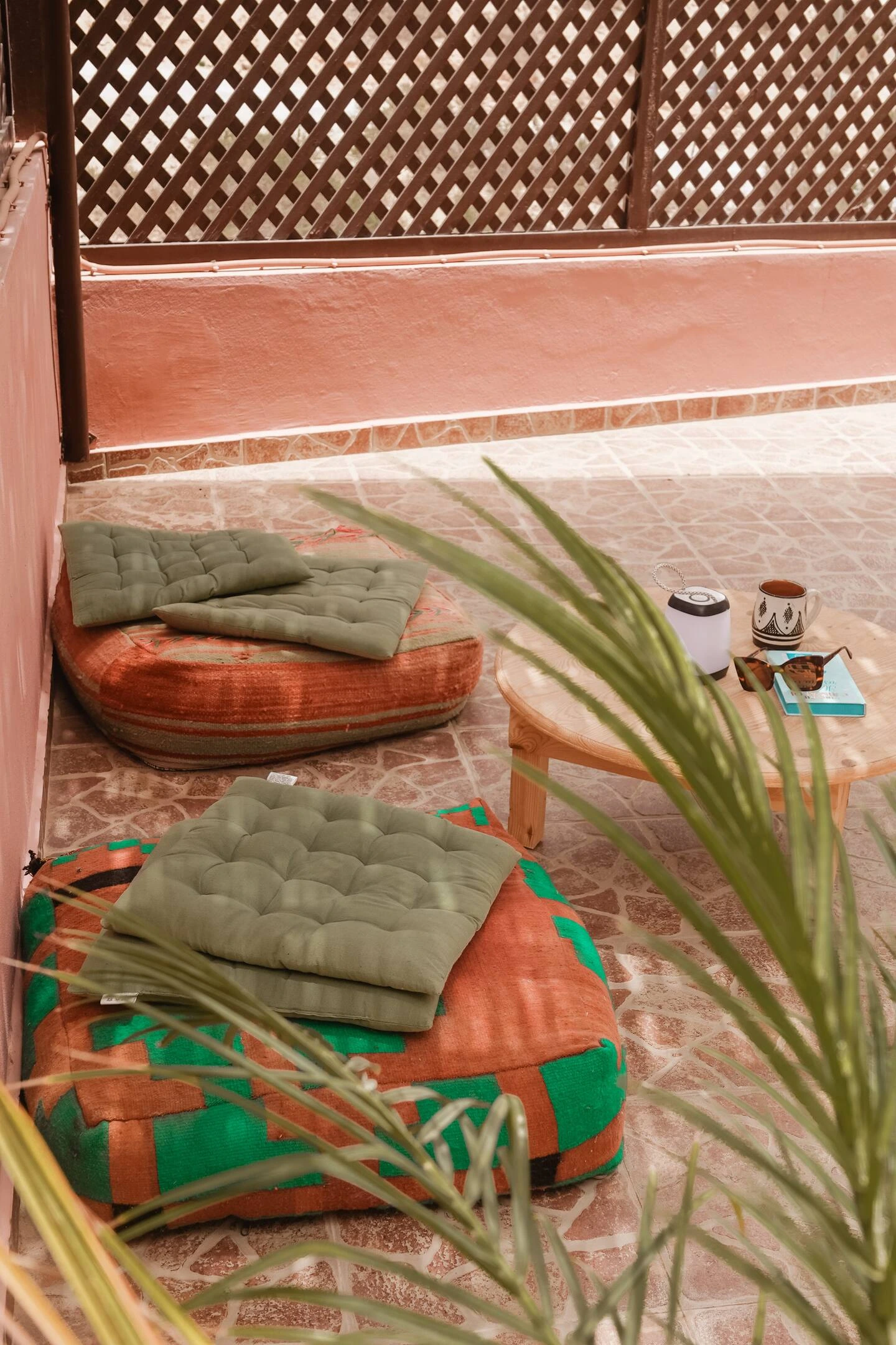 Coussins marocains sur la terrasse arborée du Berber Shelter à Tamraght près de Taghazout, ambiance détente et décoration artisanale.
