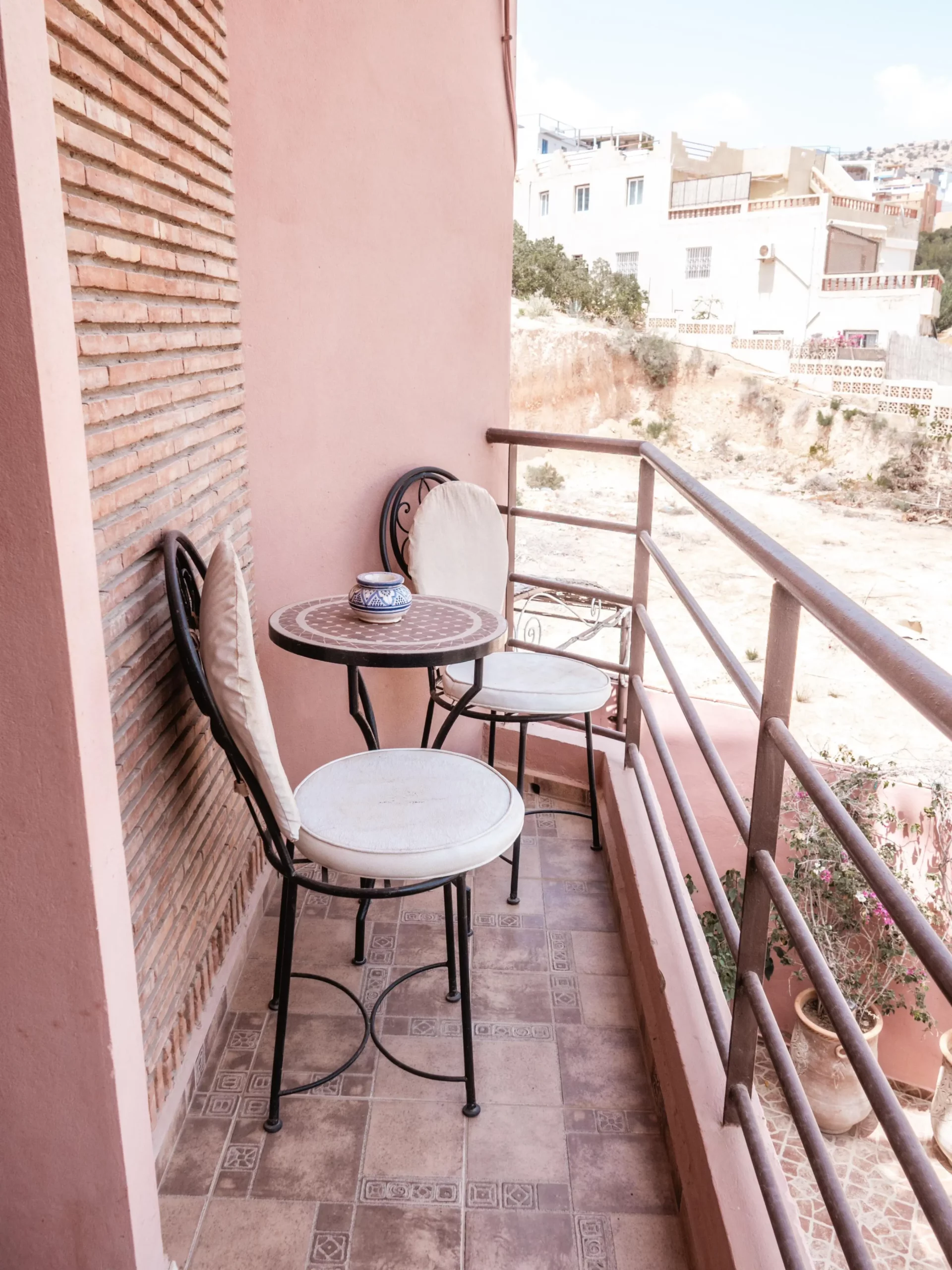 Balcon privé de l’appartement Ayour à Berber Shelter, maison d’hôtes à Tamraght près de Taghazout, avec table et chaises et vue sur le village.