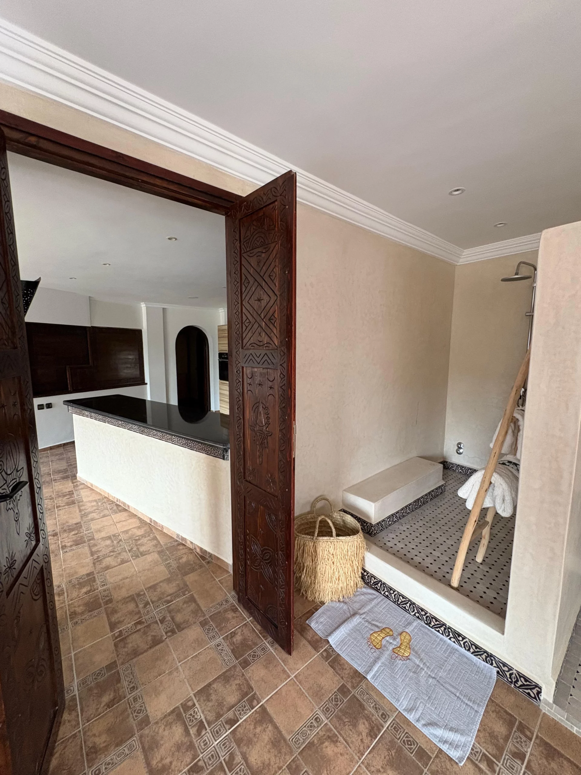 Suite Itri à Berber Shelter, Tamraght près de Taghazout : vue depuis la chambre sur la douche à l’italienne intégrée et la cuisine ouverte, dans un style marocain contemporain.